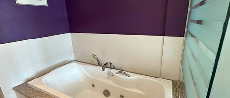 Un baño moderno con una bañera independiente, azulejos blancos y encimera de granito.