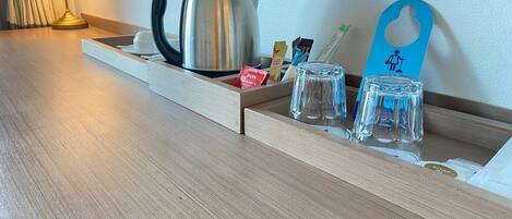 A wooden tray with a kettle, glasses, and a blue card with a toilet symbol.