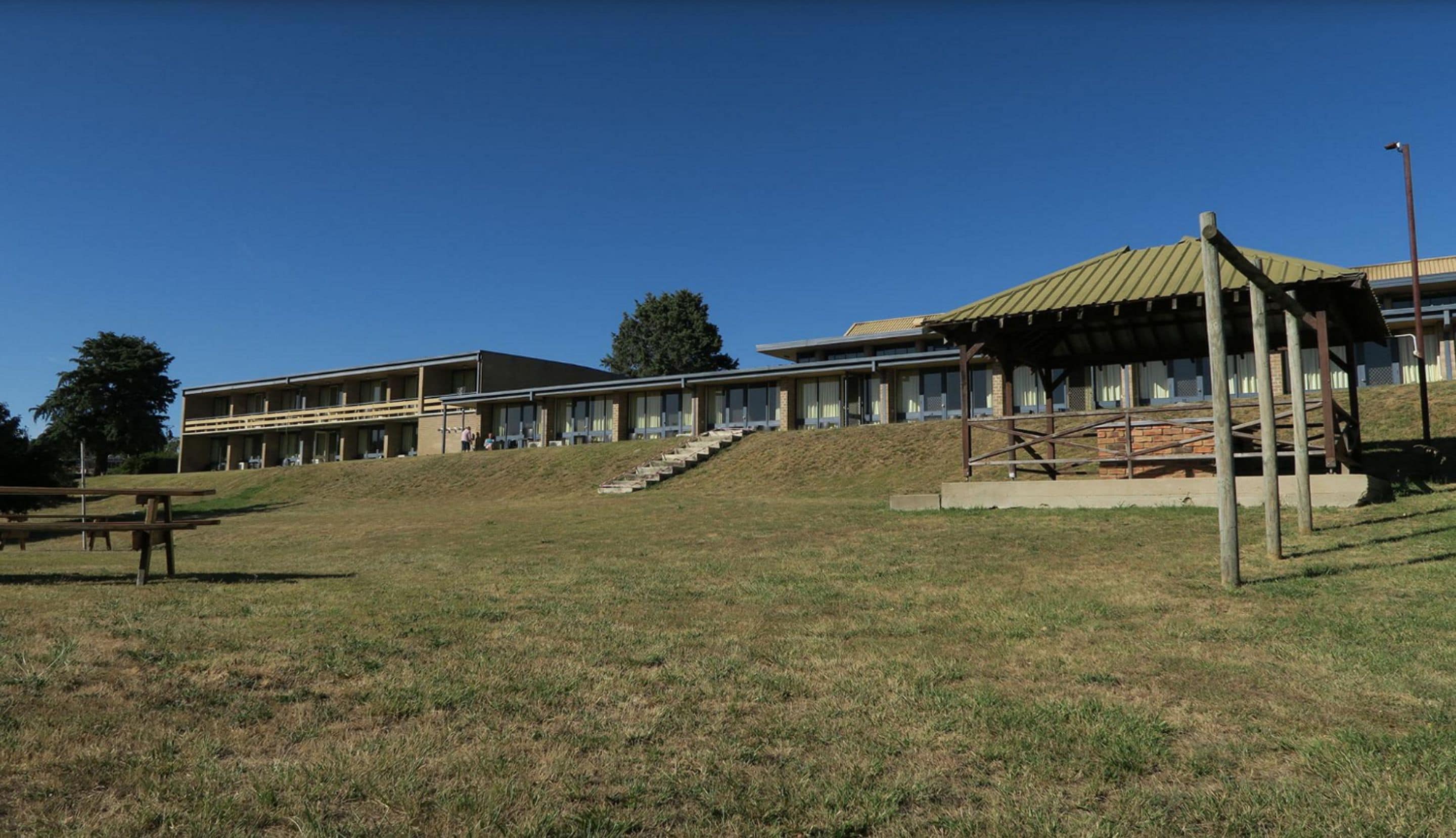 A building with a flat roof, a covered outdoor area, and a staircase leading up to it.