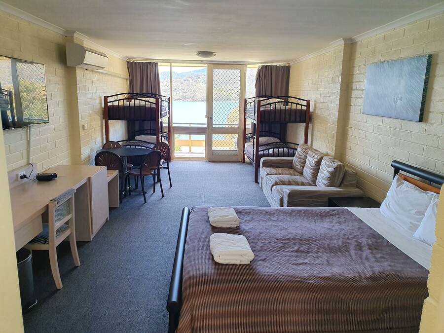 Ein Zimmer mit Etagenbetten, einem Schreibtisch, einem Sessel, einer Couch und einem Bett.