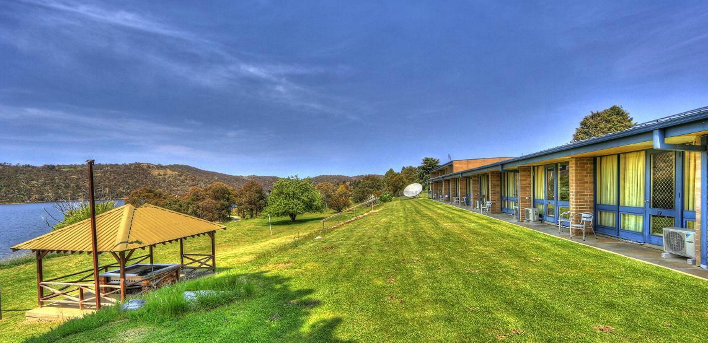 Un hotel con un área exterior techada, piscina y vistas del paisaje circundante.