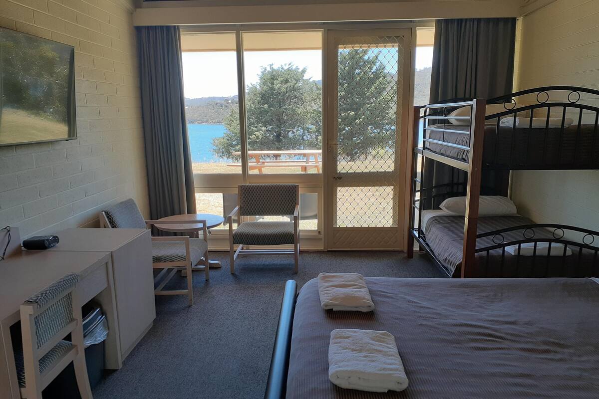 Une chambre d’hôtel équipée d’un bureau, d’une chaise, de lits superposés et offrant une vue sur la mer.