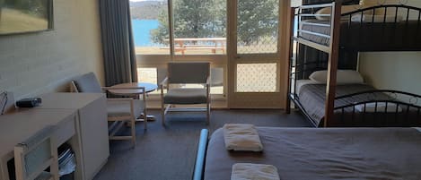 Ein Hotelzimmer mit Schreibtisch, Stuhl, Etagenbetten und Meerblick.