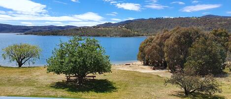 A lakeside view with a wooden deck and picnic tables.