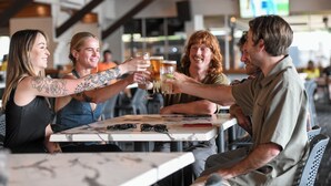 Un groupe de personnes trinquant autour d’une table dans un restaurant à l’ambiance décontractée.