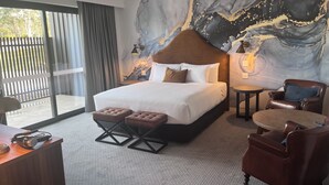 Une chambre d’hôtel moderne, dotée d’un grand lit, d’un bureau, d’une chaise et offrant une vue sur l’extérieur.
