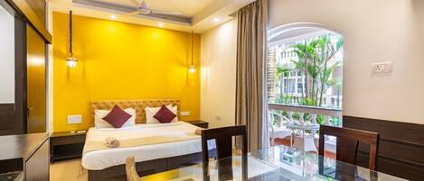Habitación de hotel con cama, una mesita de vidrio y vista a palmeras.