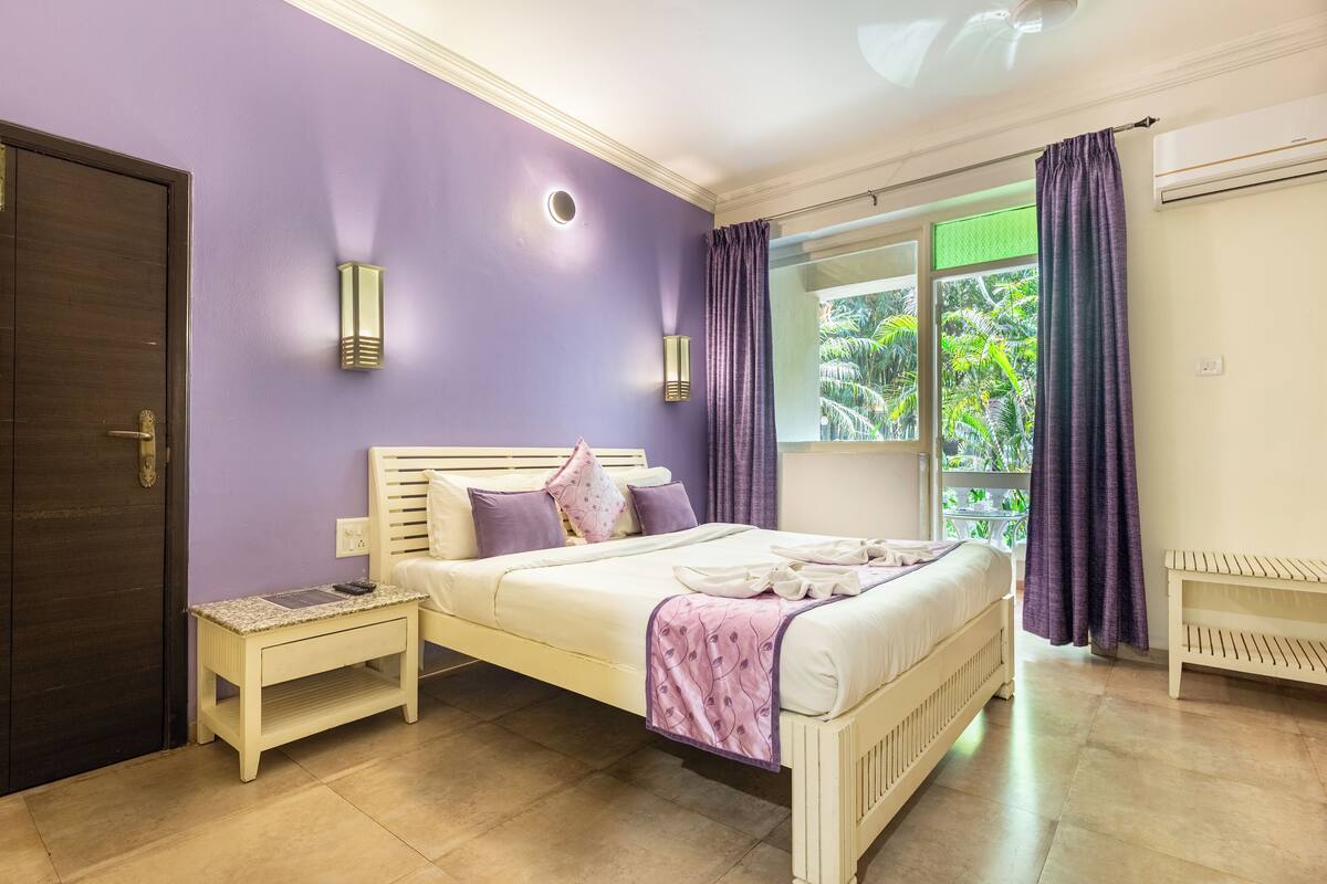 A bedroom with a bed, bedside tables, a window with curtains, and a door.