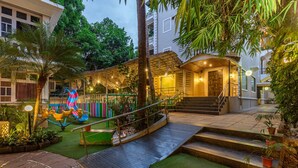 Un espacio exterior bien iluminado con una escalera, césped artificial y un parque infantil.