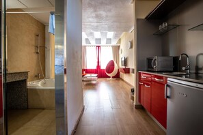 Una cocina moderna con armarios rojos, microondas integrado y refrigerador.
