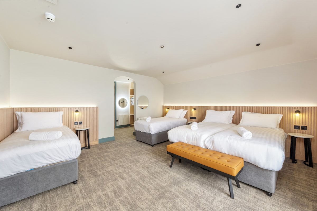 Une chambre d’hôtel avec deux lits, un banc et une petite table.