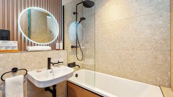 A modern bathroom with a white sink, a glass-enclosed shower, and a large mirror.