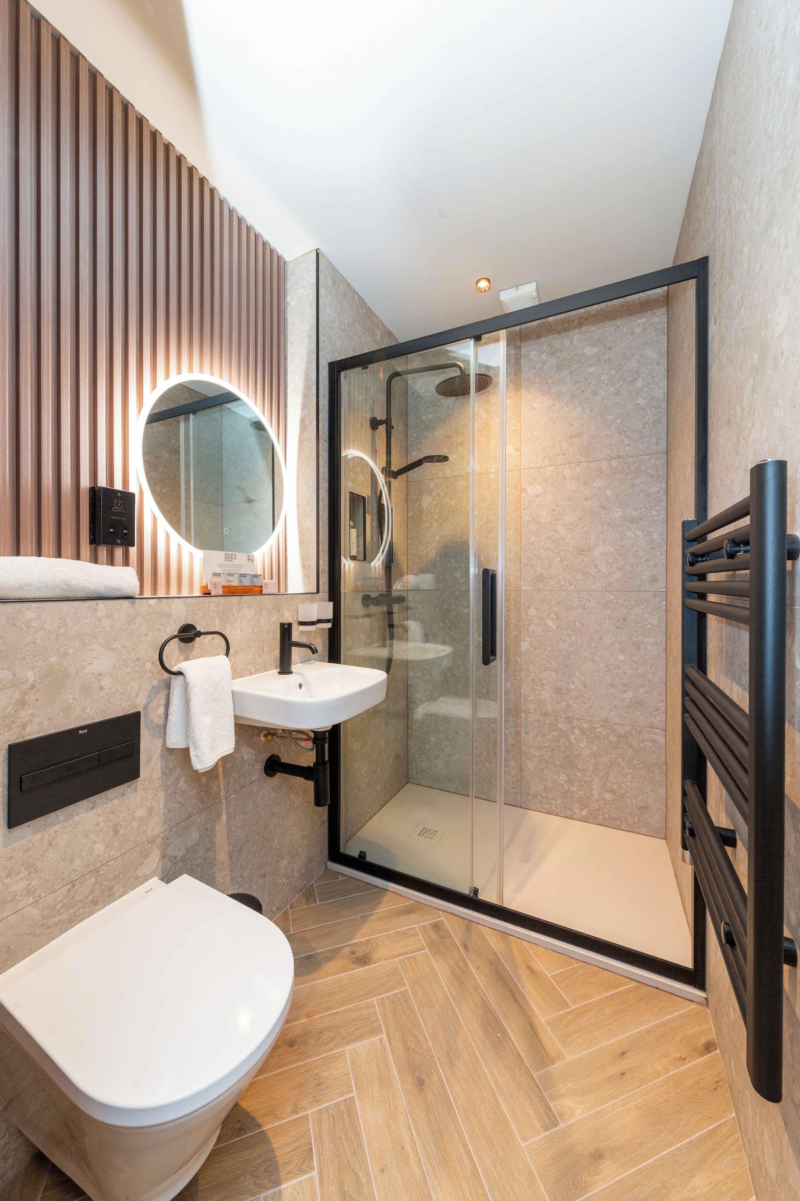 A modern bathroom with a toilet, sink, and glass-enclosed shower.