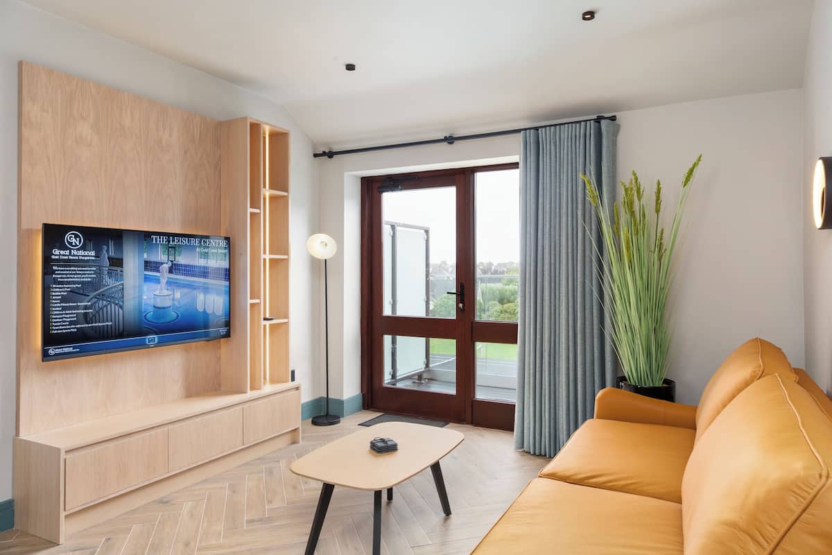 Un salon moderne avec un téléviseur à écran plat fixé à un mur en bois, un canapé, une table basse et une grande fenêtre avec des rideaux.