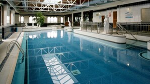 Una piscina interior con agua cristalina, un trampolín y una estatua de socorrista.