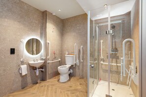 Een moderne badkamer met een douchecabine van glas, een wit wastafelmeubel en een toilet.