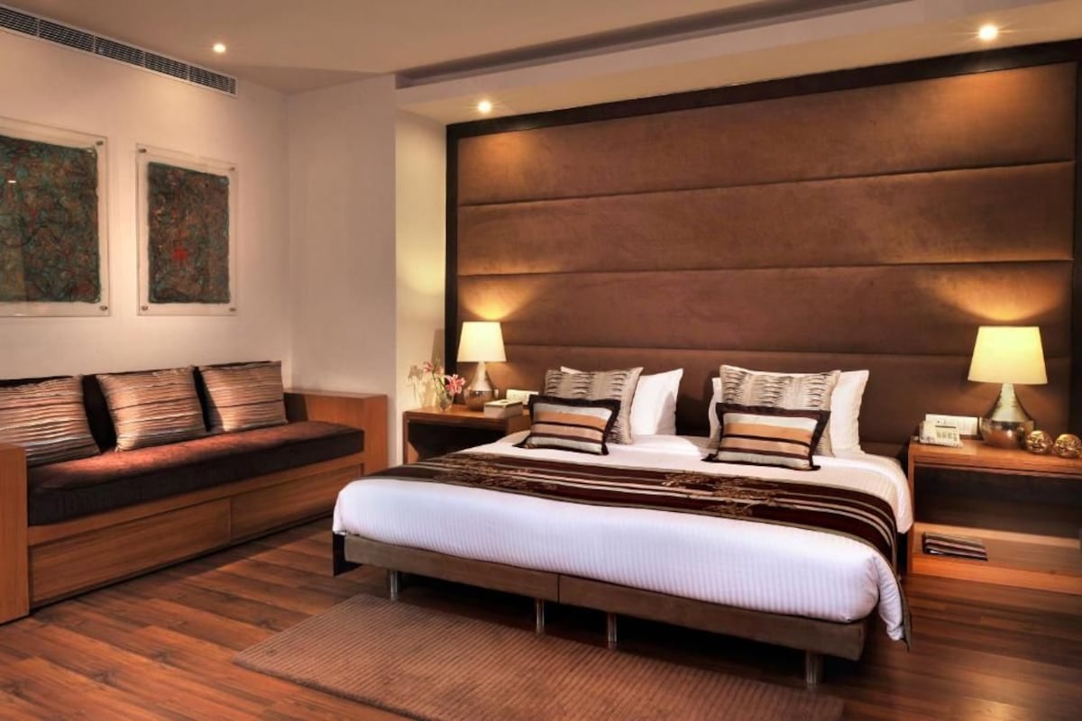 Une chambre d’hôtel moderne avec un grand lit, un banc en bois et deux tables de chevet équipées de lampes.