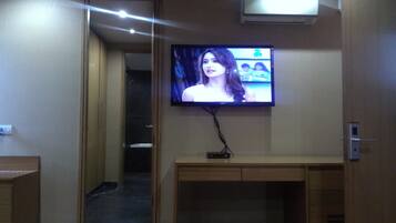 A television mounted on a wall in a hallway with a wooden cabinet below.
