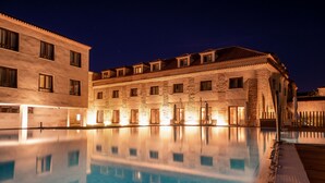 Hotel amb una gran piscina exterior, façana de pedra i nombrosos balcons.