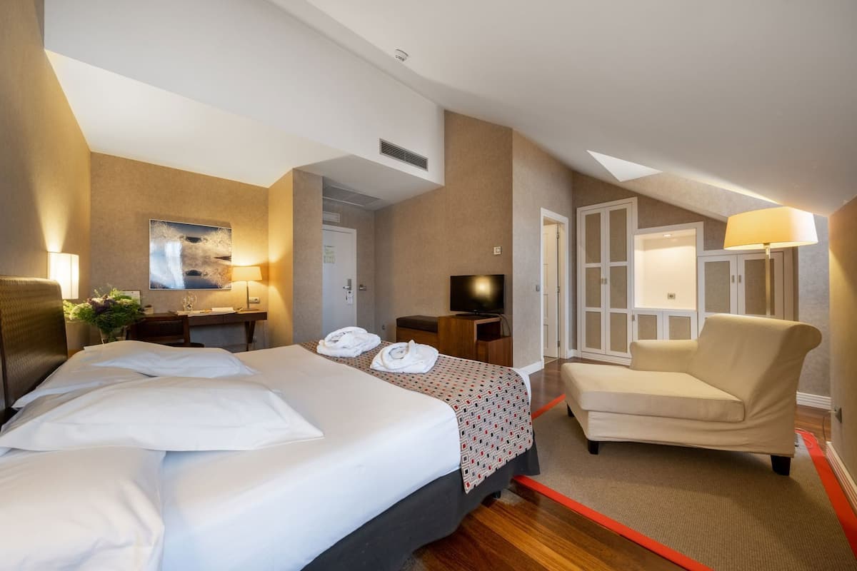Una habitación de hotel con cama, escritorio, silla, televisor y armario.