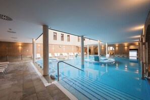 An indoor swimming pool with clear lanes, lounge chairs, and a brick wall backdrop. - Castilla Termal Balneario de Olmedo (Olmedo)