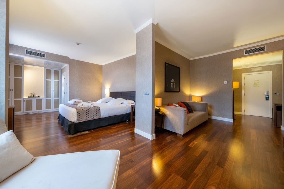 Una habitación de hotel con cama, sofá, escritorio y una silla.