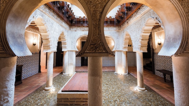 Un pati interior amb arcs, columnes i un paviment de rajoles amb dibuixos.