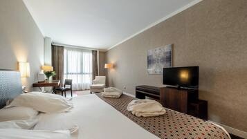 Una camera d'albergo con un letto grande, una scrivania con una sedia, una televisione e vista sull'esterno dalla finestra.