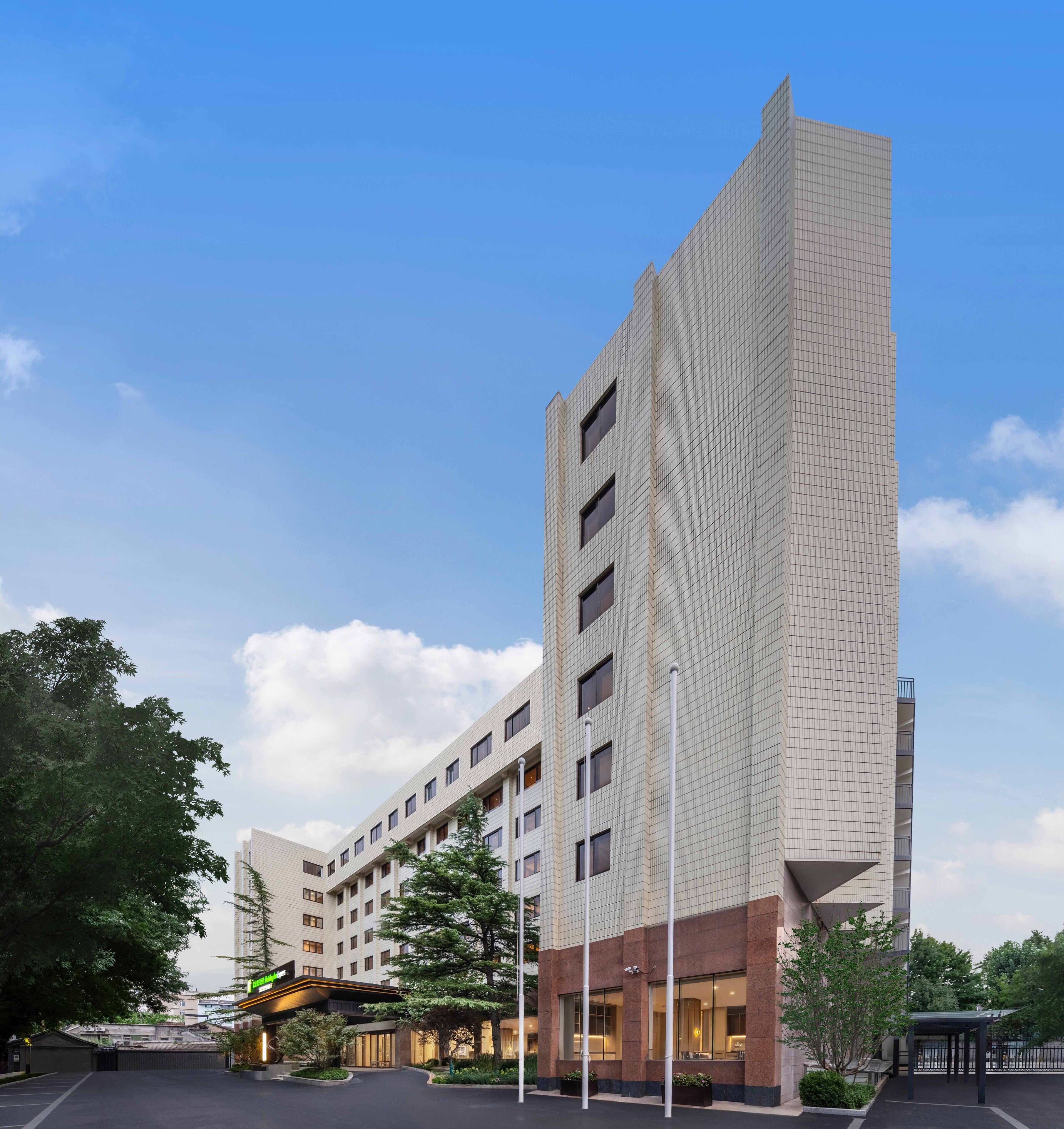 Un hotel moderno con un ingresso d'angolo ben visibile, diversi piani e una facciata in vetro e mattoni.