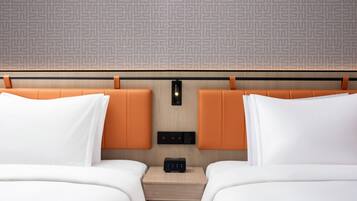 A hotel room with two beds, a nightstand, a wall-mounted light, and a patterned wallpaper.