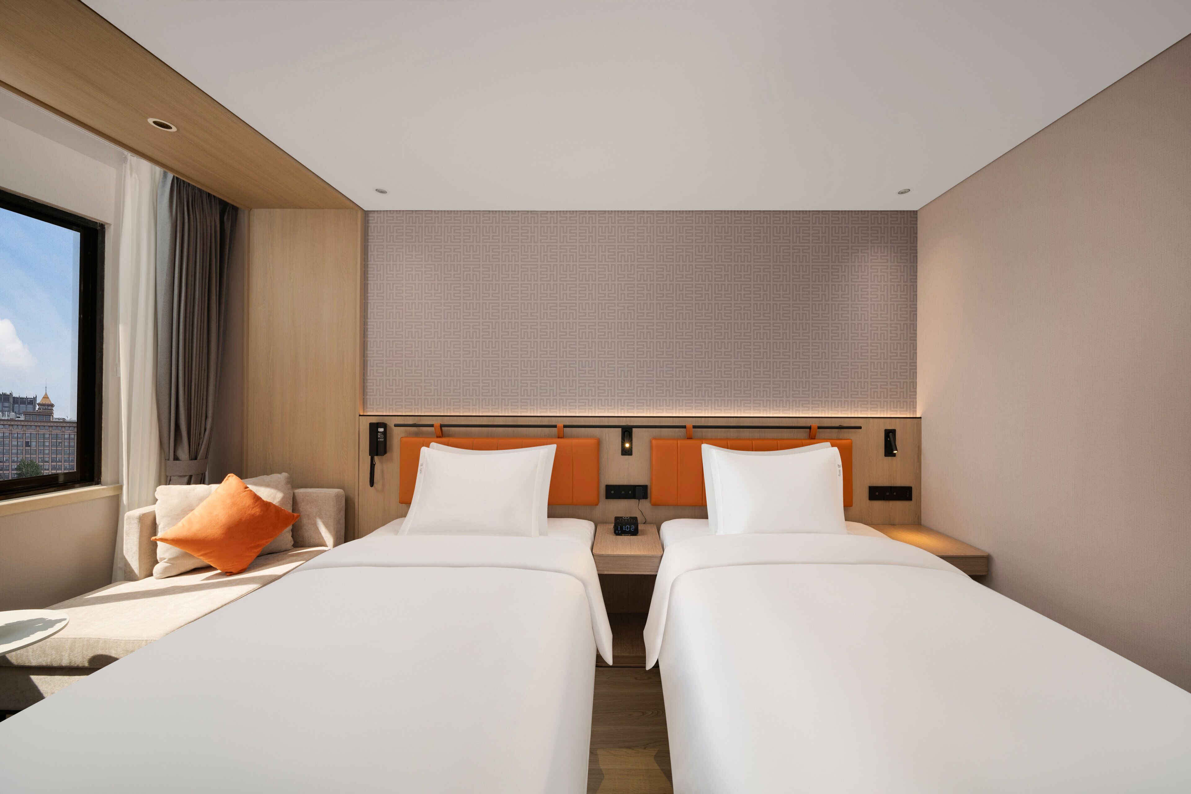 A hotel room with two beds, a desk, a telephone, and a window with curtains.