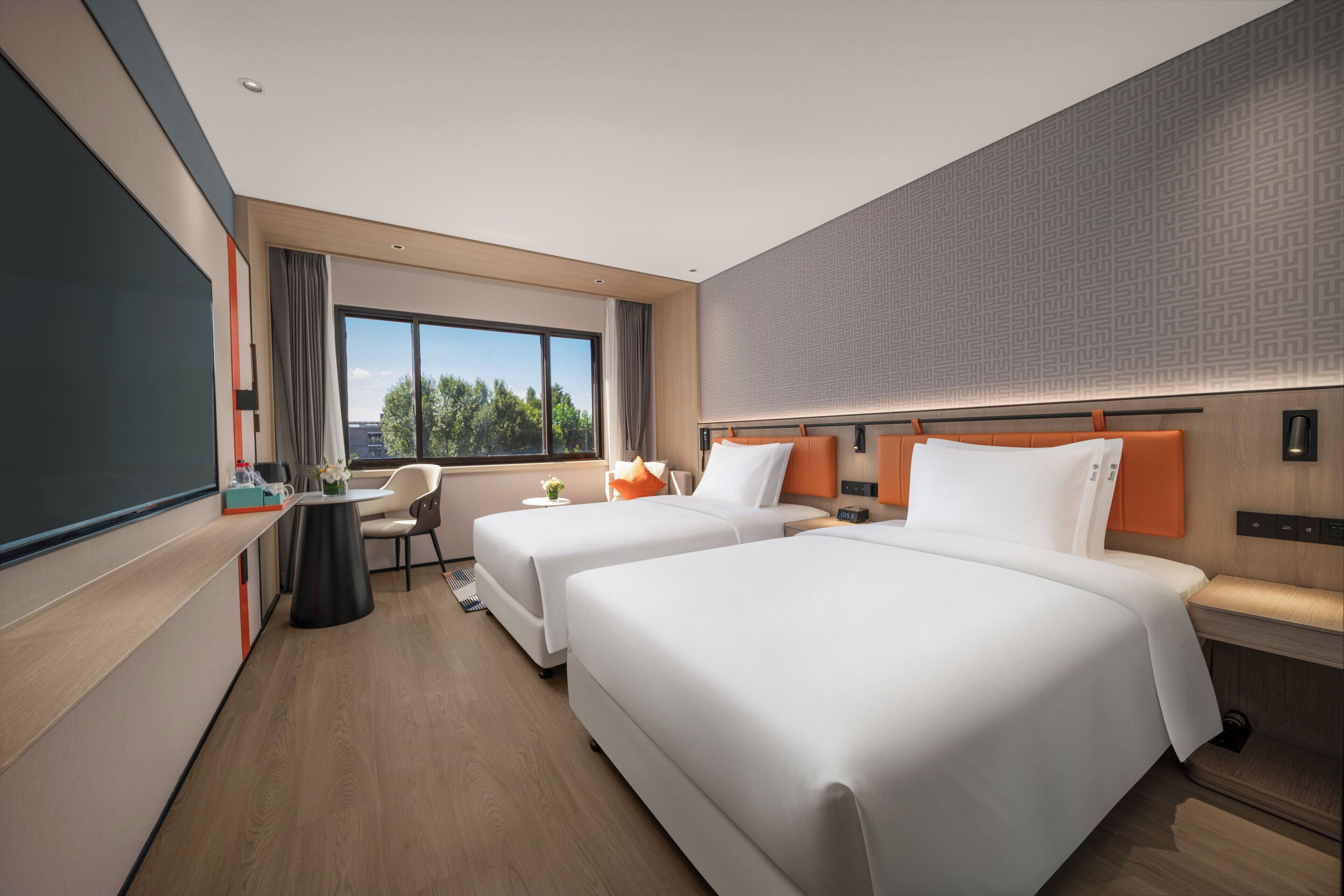 A hotel room with two beds, a desk, a chair, a window with a view, and a minibar.