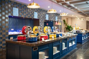 A buffet area with multiple food stations, each with a different colored serving bowl.