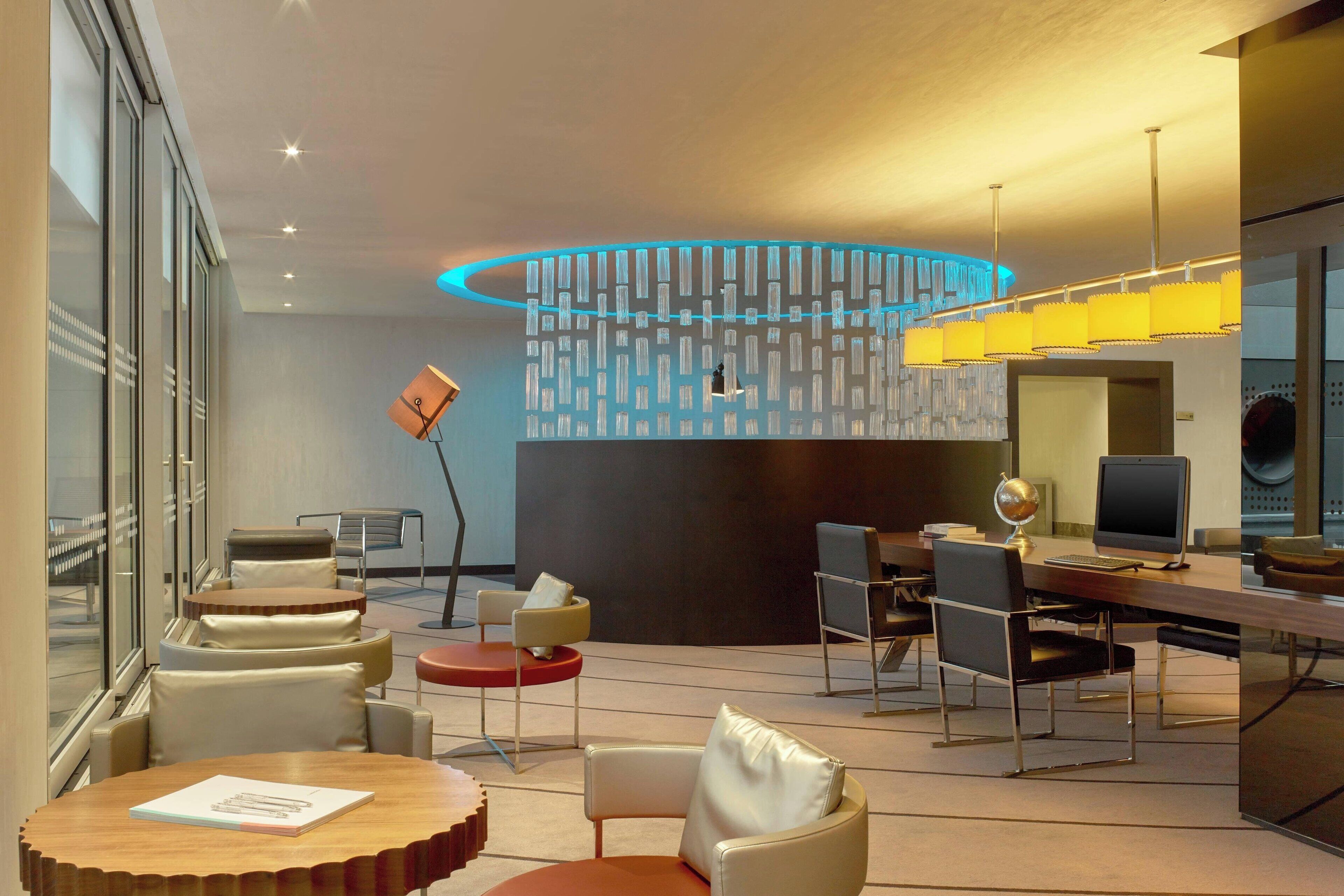 Un moderno vestíbulo de hotel con un área de estar central, una recepción y un amplio ventanal con vistas a la ciudad.