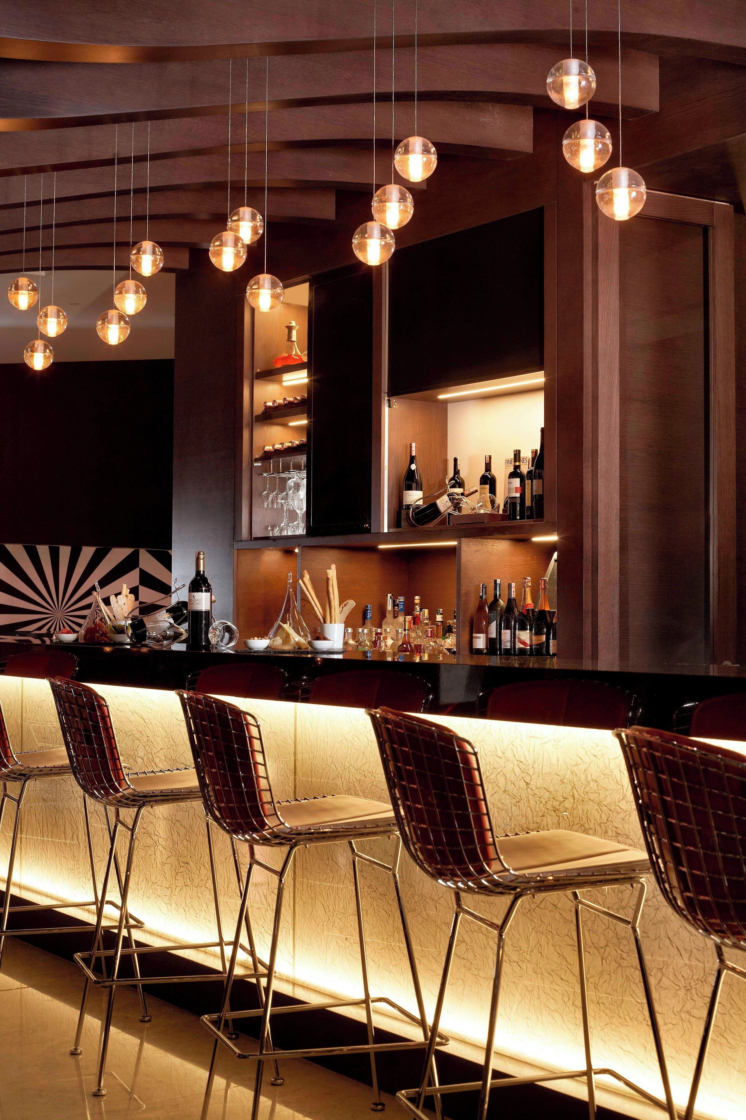 A bar area with hanging spherical light fixtures, a bar counter, and metal chairs.