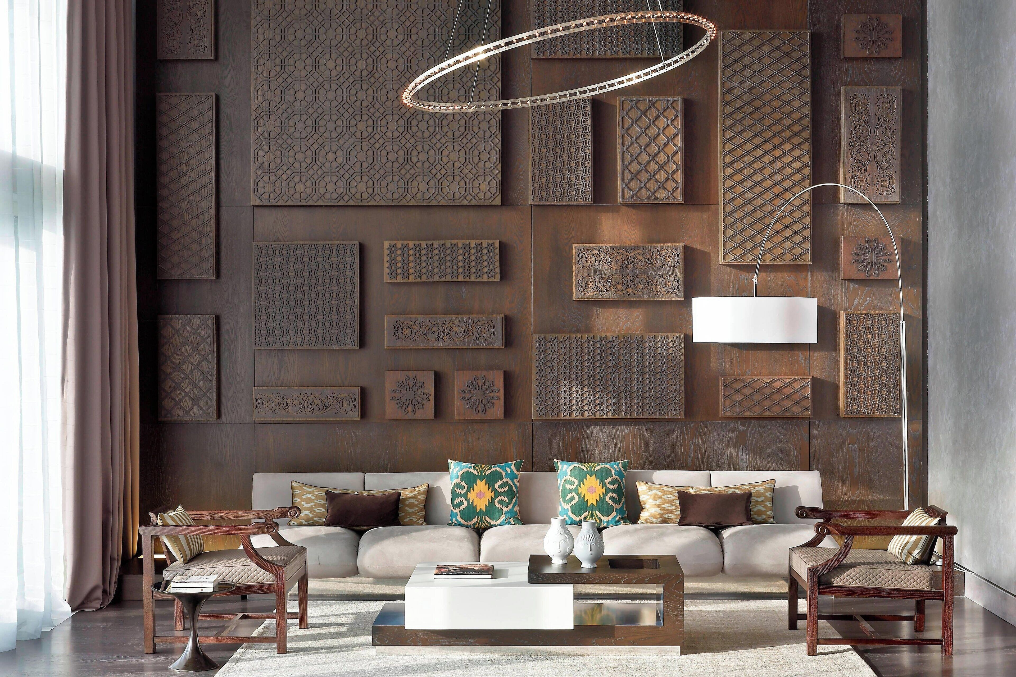 A modern living room with a sofa, two armchairs, a coffee table, and a decorative wall with geometric patterns.