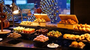 A variety of baked goods displayed on trays and in boxes, with a decorative light fixture in the background. - Le Meridien Istanbul Etiler (Istanbul)