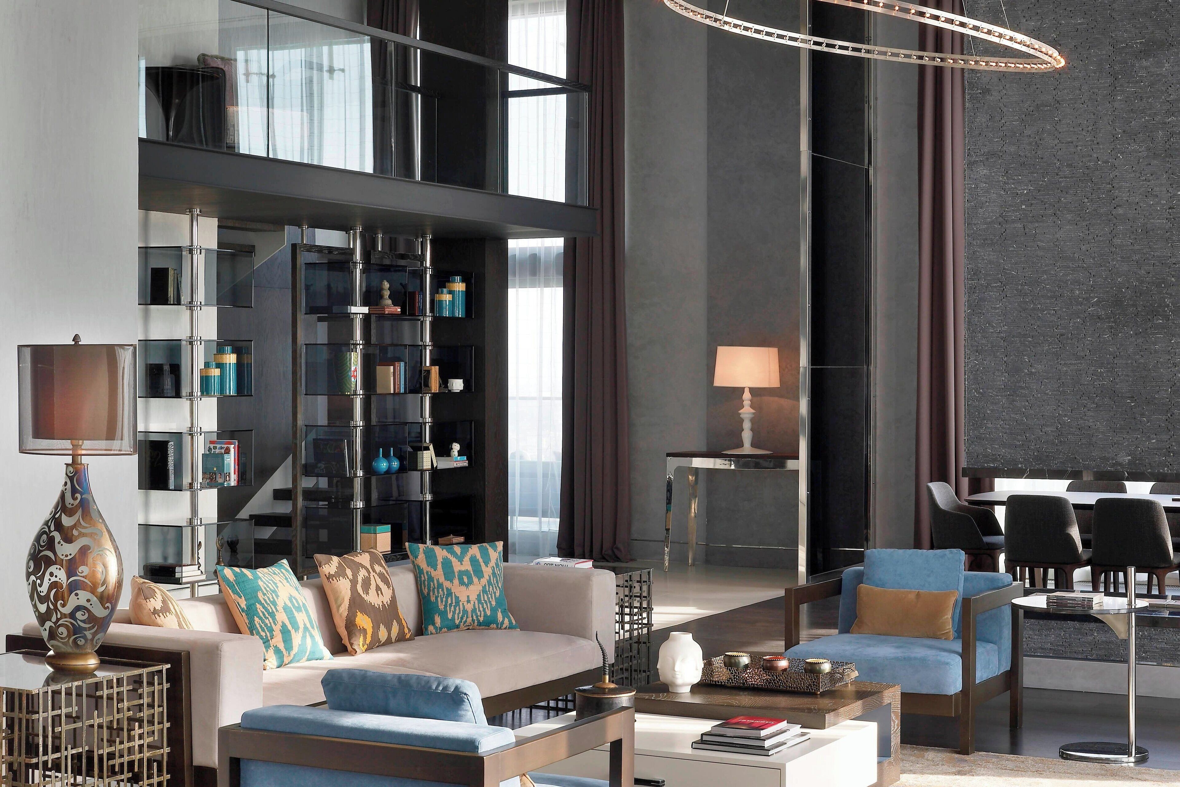 Una sala de estar moderna con un sofá, sillones, una mesa de centro y una estantería.