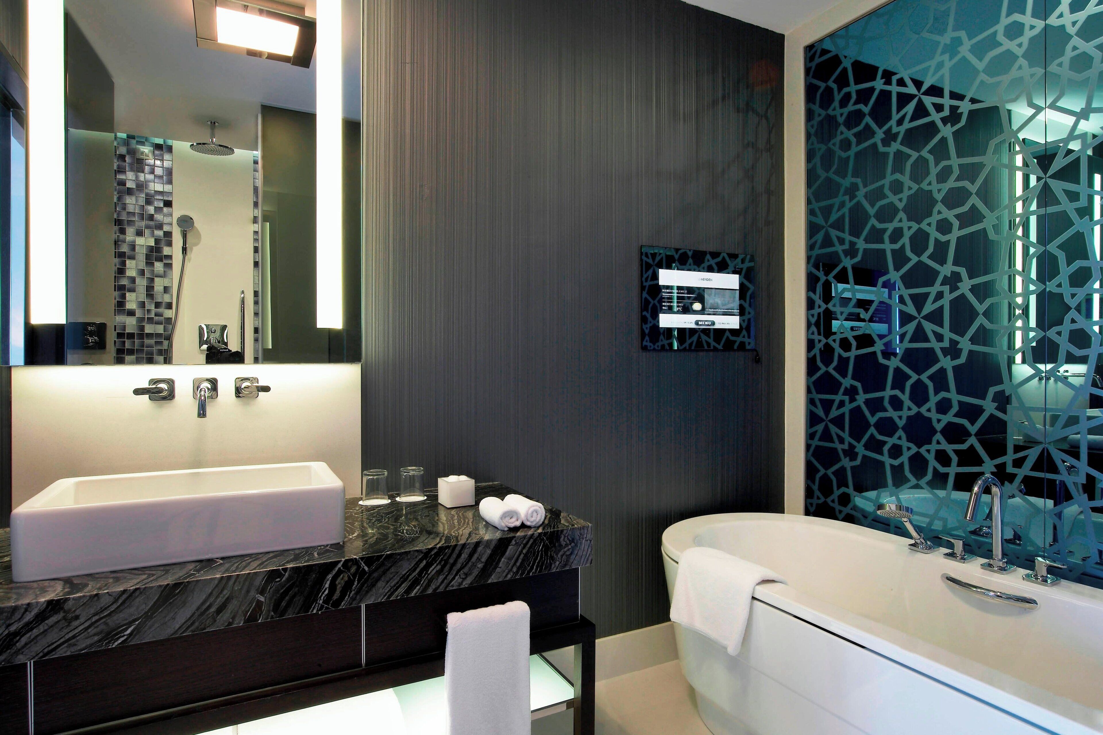 A modern bathroom with a large rectangular sink, a freestanding bathtub, and a large mirror.