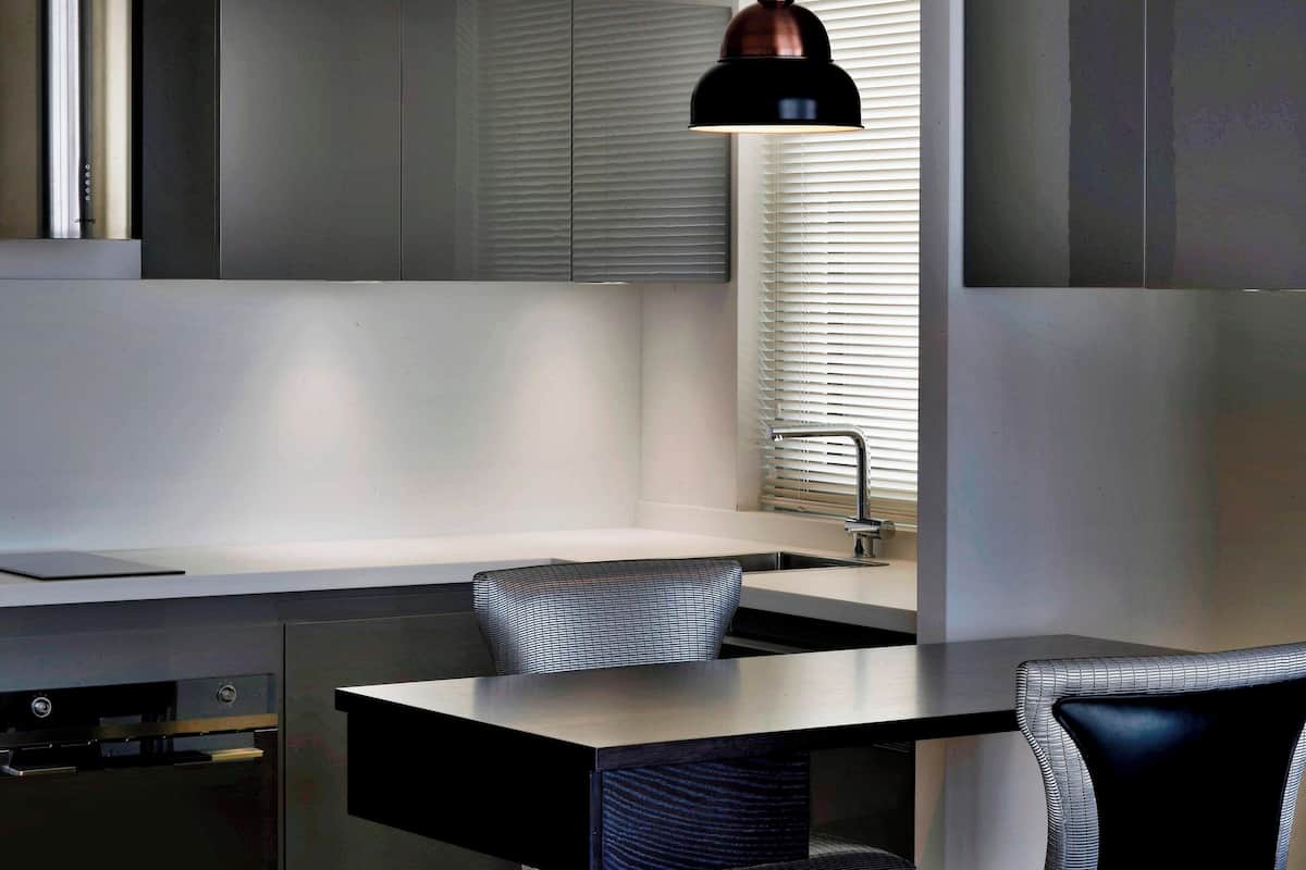 A modern kitchen with a built-in oven, a sink, and a dining area with a table and chairs.