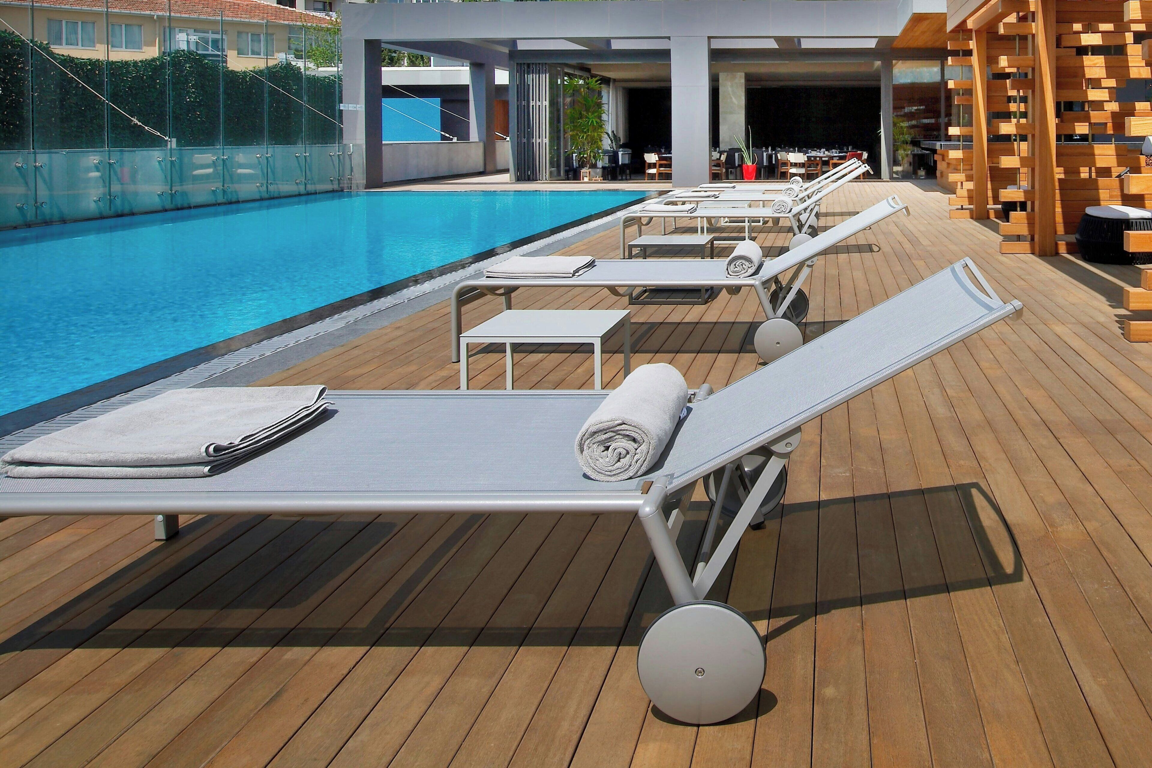 Ein Poolbereich mit Liegestühlen, einer Holzterrasse und einem klaren, blauen Pool.