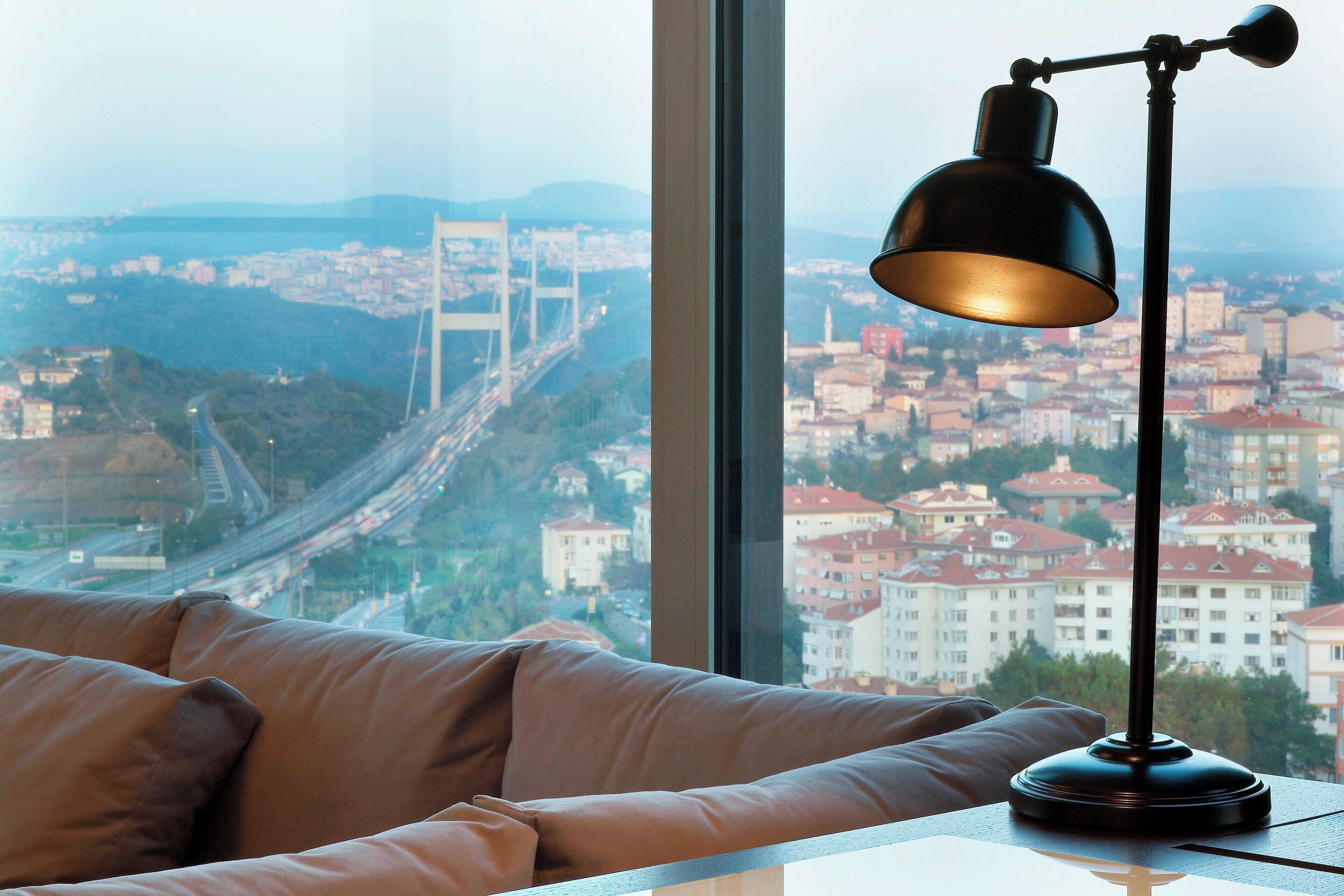 A room with a view of a bridge and cityscape through a large window.