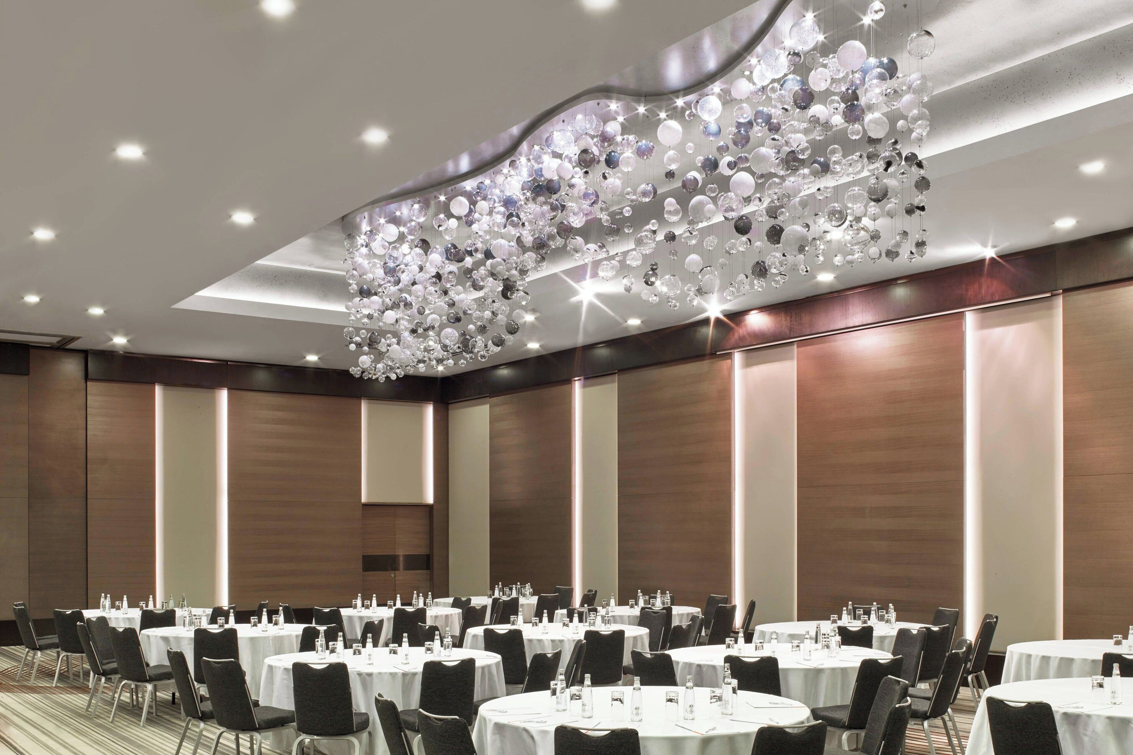 A conference room with round tables, chairs, and a decorative chandelier.