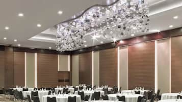 A conference room with round tables, chairs, and a decorative chandelier.