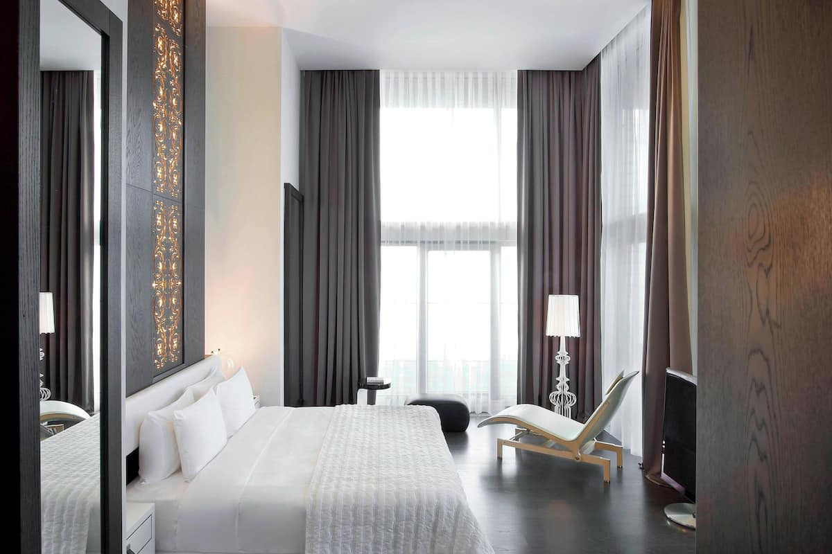 A hotel room with a large bed, a chair, a desk, and a TV.