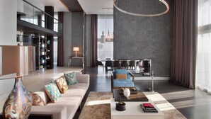 A modern living room with a sofa, coffee table, and decorative pillows. There is a dining area with a table and chairs in the background. - Le Meridien Istanbul Etiler (Istanbul)