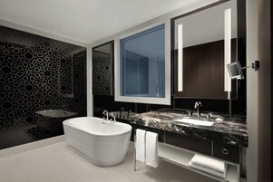 Un baño moderno con una bañera independiente, un espejo grande y una encimera de mármol.