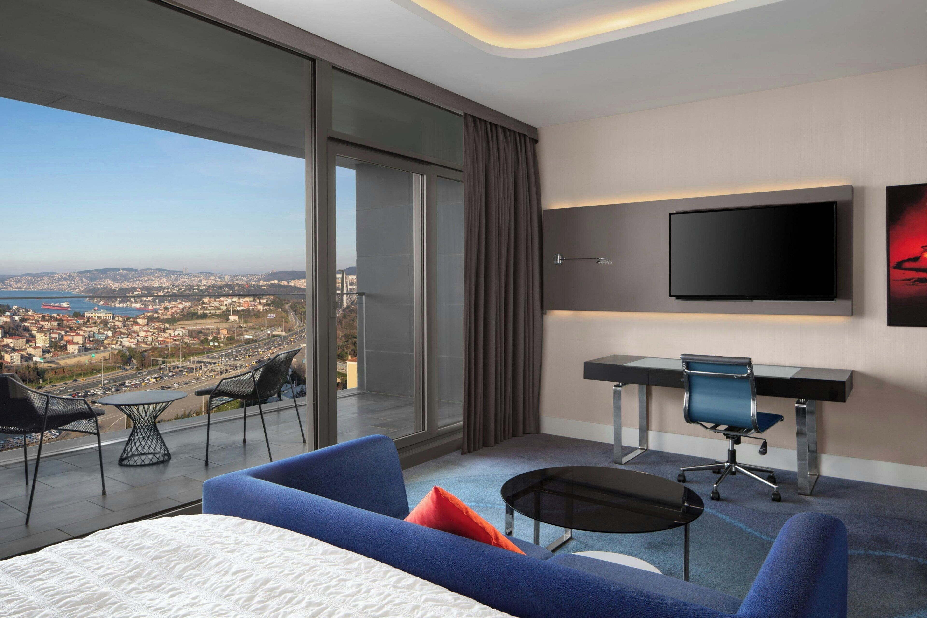 Una habitación de hotel moderna con una cama grande, un escritorio, una silla y un televisor.