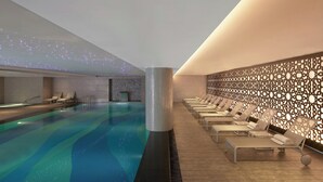 A modern indoor pool with clear water, surrounded by lounge chairs and a decorative wall with cut-out patterns. - Le Meridien Istanbul Etiler (Istanbul)