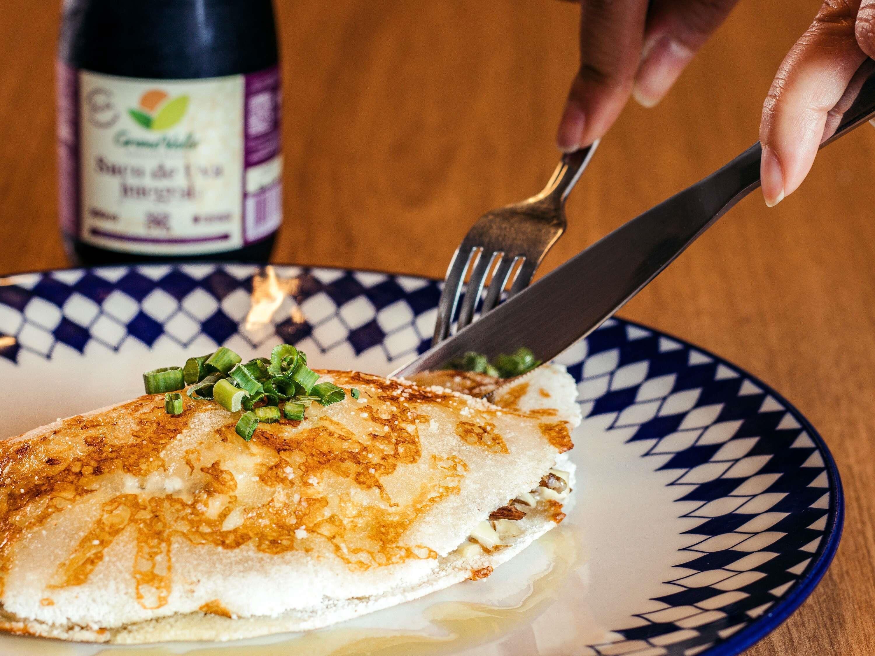 A plate with a food item, a bottle, and a fork on a table.